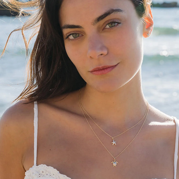 Woman wearing a necklace with a star pendant in front of a blurred natural background