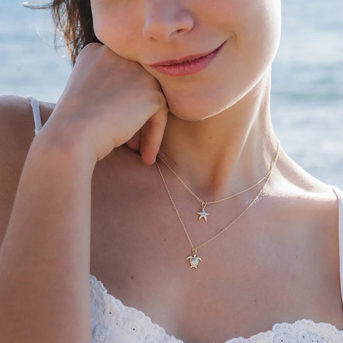 Smiling woman wearing White Sapphire Turtle Necklace at sunny beach
