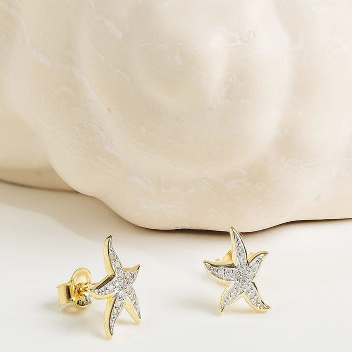 Gold starfish earrings on a light background