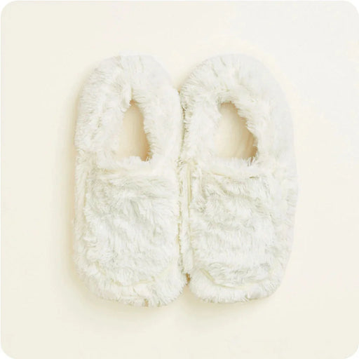 Pair of white fuzzy slippers on a light beige background