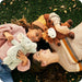 Two people lying on grass with stuffed animals