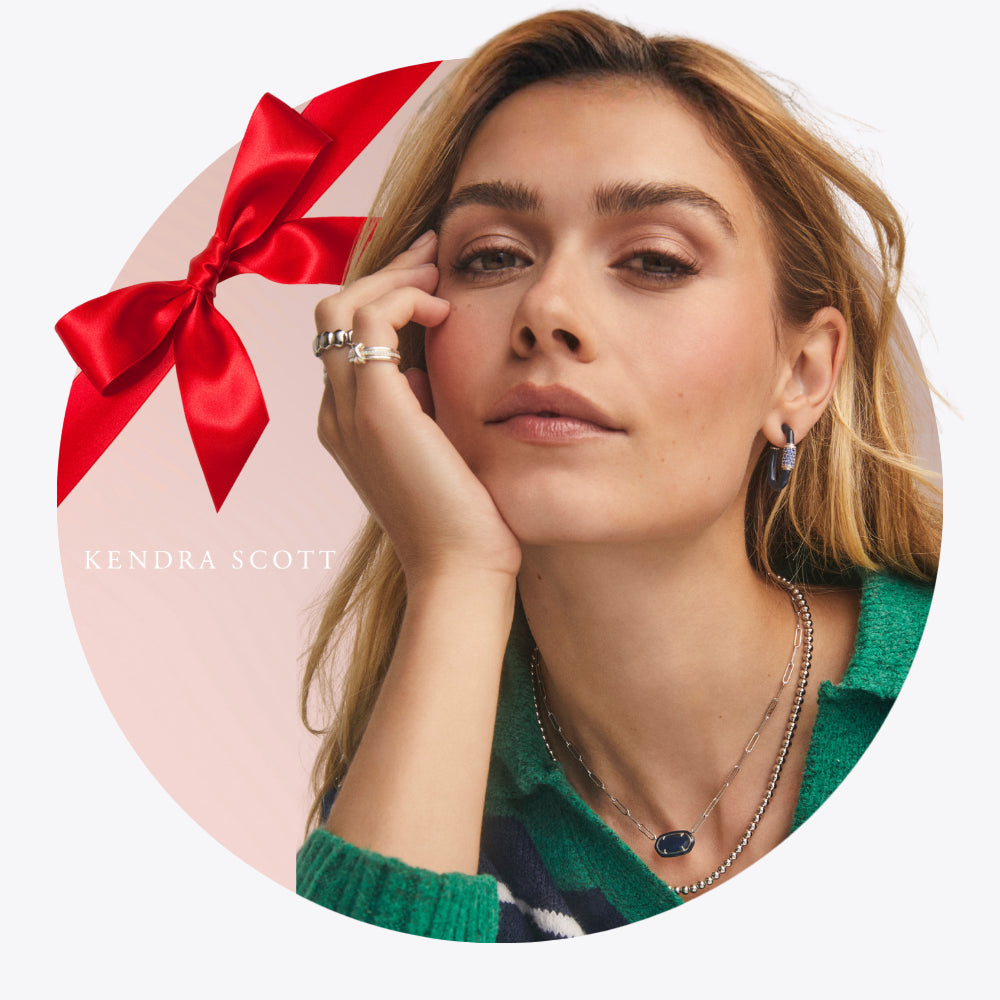 Woman wearing jewelry with a red bow and 'Kendra Scott' branding