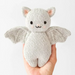 Cuddle + Kind Baby Bat in Grey – small handmade knit bat plush toy held in hand for scale.