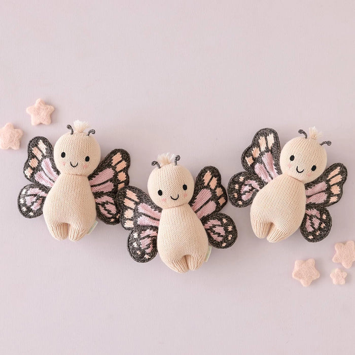 Set of three Cuddle + Kind Baby Butterfly in Peach dolls – handcrafted knit stuffed animals with wings, displayed with star accents.