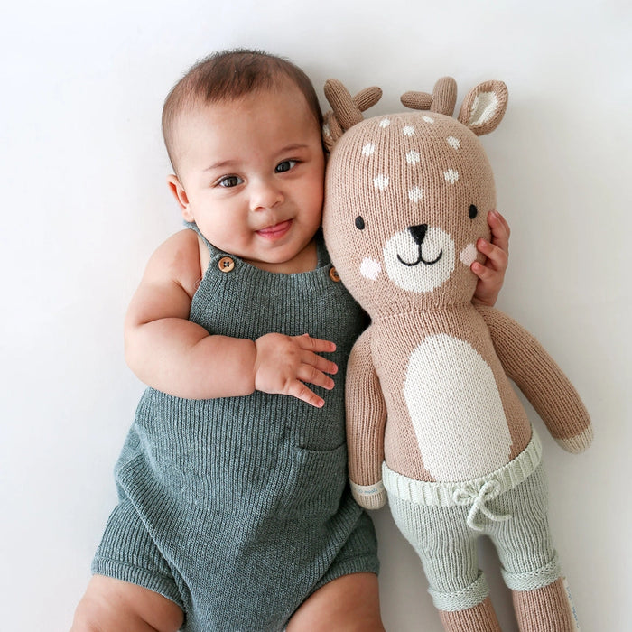 Baby cuddling with Cuddle + Kind Elliott the Fawn, large handmade knit deer doll with soft brown yarn and white spots.