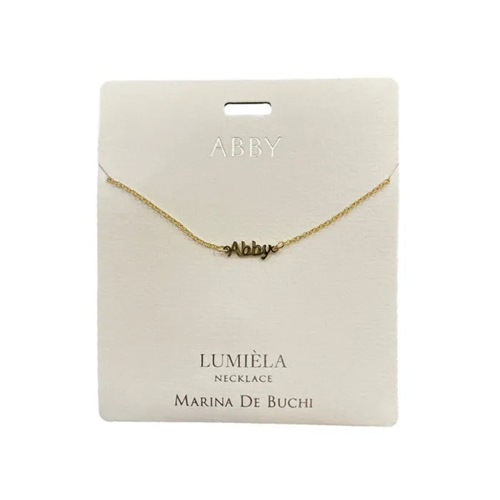 Gold necklace on a white card with 'ABBY' and 'LUMIÓLA' branding.