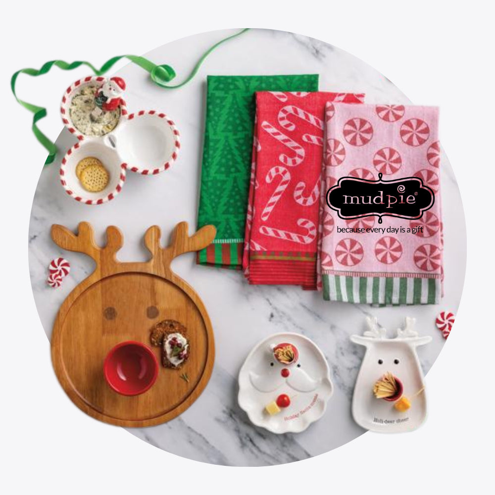 Set of Christmas-themed kitchen items including a reindeer-shaped tray, napkins, and small dishes on a marble surface with 'mud pie' branding.