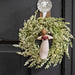 Decorative wreath with an angel figure holding a heart on a black door.