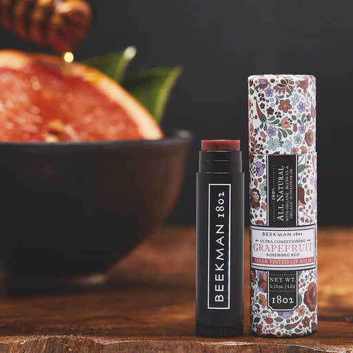 Beeckman 1802 lip balm and packaging on a wooden surface with a blurred background